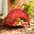 Dog lying on a red portable pet canopy on a sunny patio.

